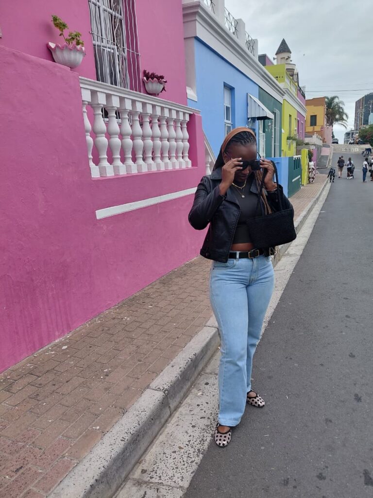 Travel blogger Linet Kingaru exploring the vibrant, colorful houses of the historic Bo-kaap neighborhood in Cape Town.