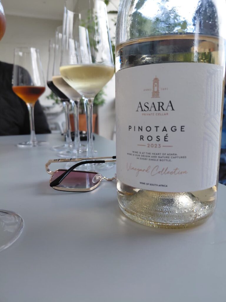 A bottle of Asara Pinotage Rosé and wine glasses at a vineyard during a budget-friendly Cape Winelands day trip near Cape Town.