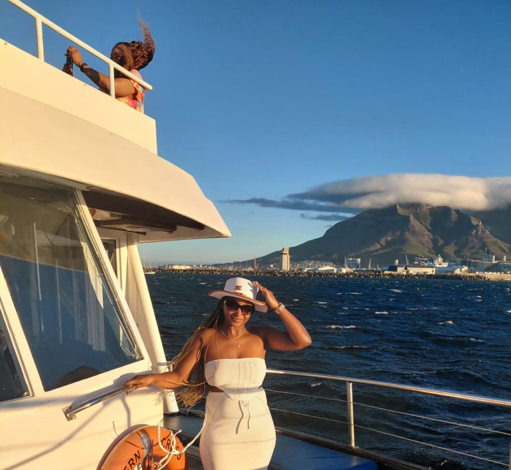 Travel blogger Linet Kingaru on a scenic boat cruise with views of Table Mountain, South Africa.